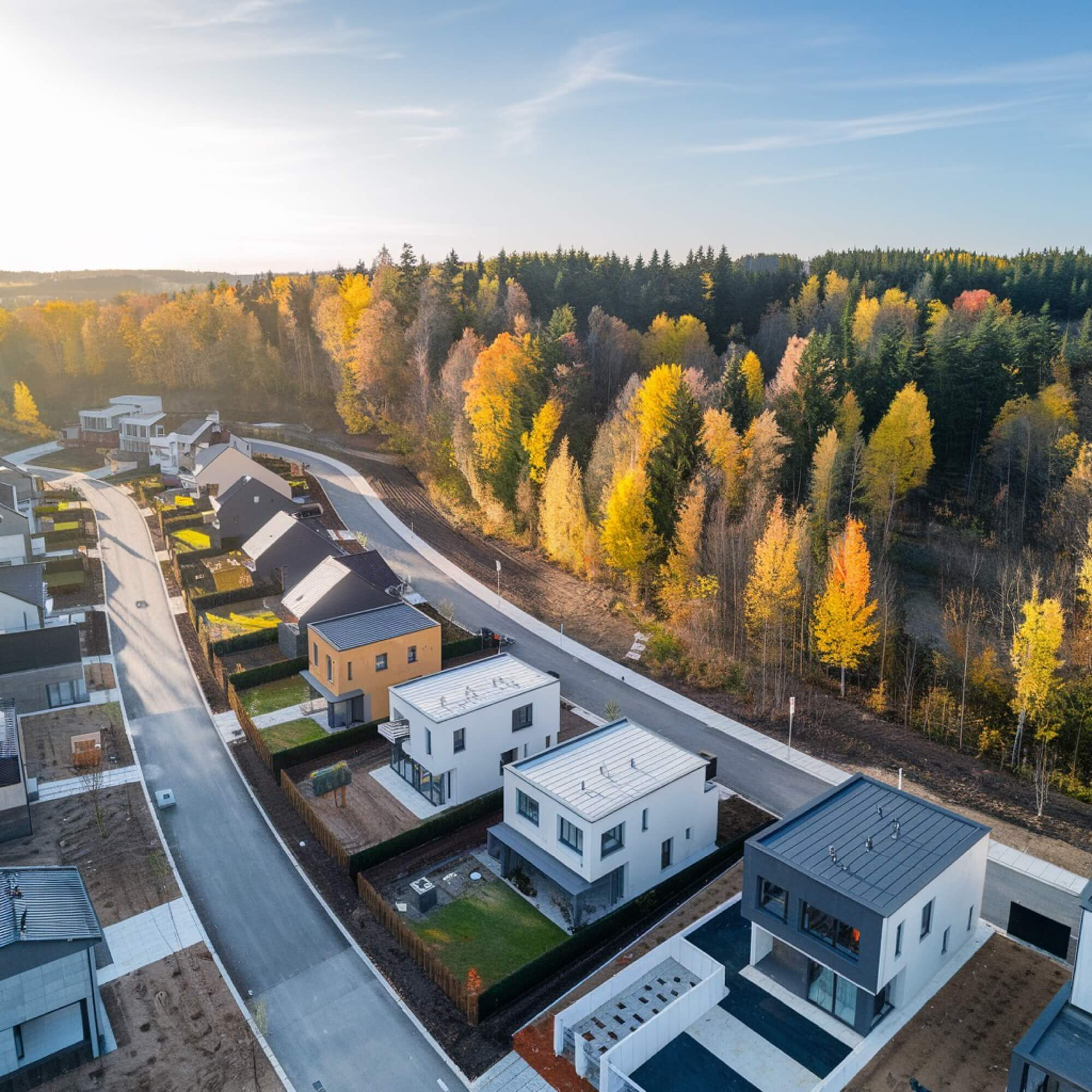 Flygfoto över ett nytt bostadsområde med moderna villor, ett exempel på storskalig nybyggnation.